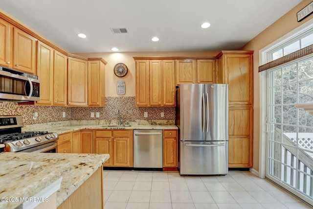 kitchen with light stone countertops, visible vents, a sink, decorative backsplash, and appliances with stainless steel finishes