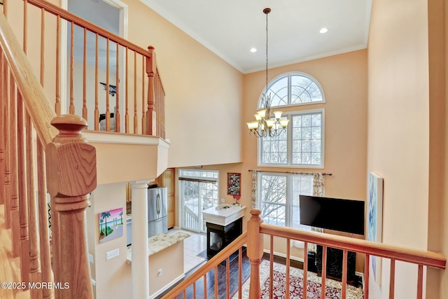 stairs with an inviting chandelier, a high ceiling, recessed lighting, and crown molding