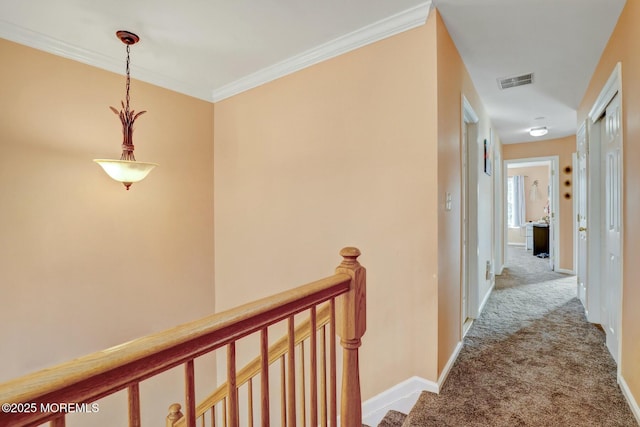 hall featuring visible vents, baseboards, carpet, ornamental molding, and an upstairs landing