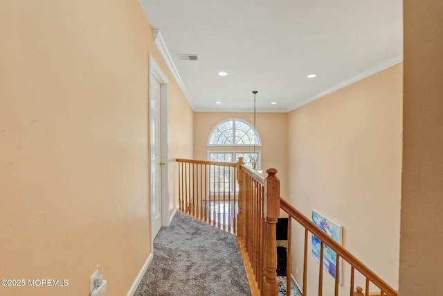 hall with an upstairs landing, carpet, visible vents, and ornamental molding