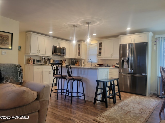 kitchen with a center island, glass insert cabinets, a breakfast bar area, appliances with stainless steel finishes, and white cabinetry