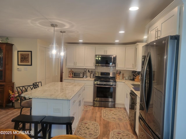 kitchen featuring white cabinets, light wood-style floors, tasteful backsplash, and appliances with stainless steel finishes