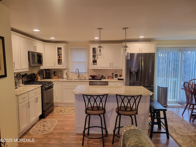 kitchen featuring hanging light fixtures, stainless steel appliances, sink, and a center island