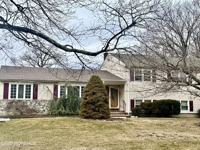 tri-level home featuring a chimney, a front lawn, and roof with shingles