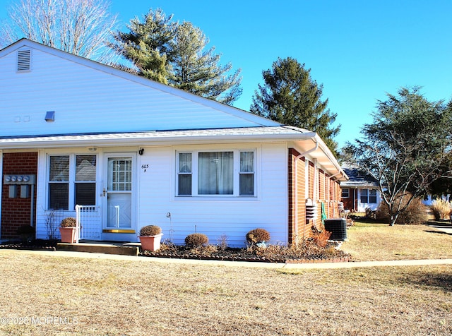 view of front of house with central AC unit and a front yard