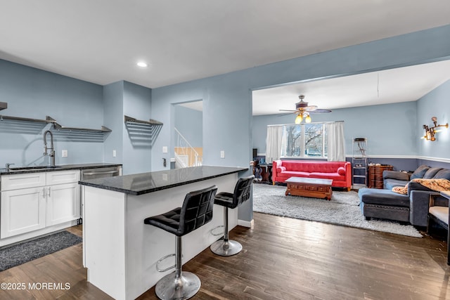 kitchen with sink, dark stone countertops, white cabinets, dark hardwood / wood-style flooring, and a kitchen bar