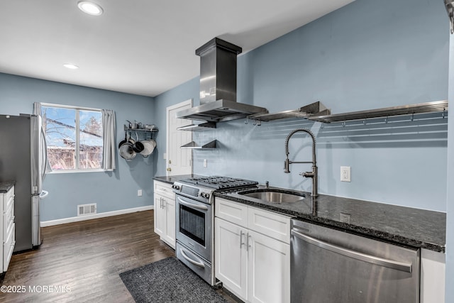 kitchen with sink, appliances with stainless steel finishes, white cabinetry, island exhaust hood, and dark stone counters