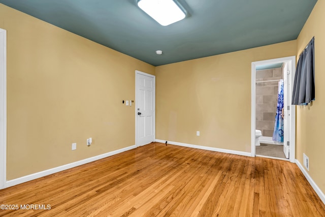 unfurnished bedroom with ensuite bath and light hardwood / wood-style floors