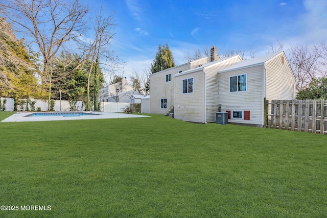 back of house with central AC unit, a yard, and a fenced in pool