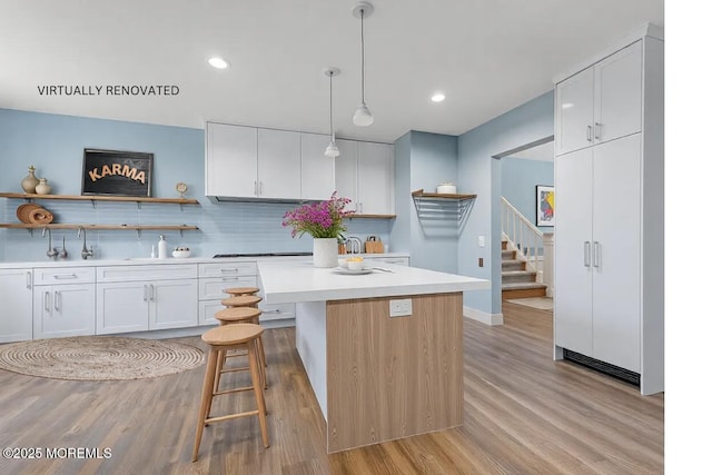 kitchen with white cabinetry, backsplash, pendant lighting, and a breakfast bar area