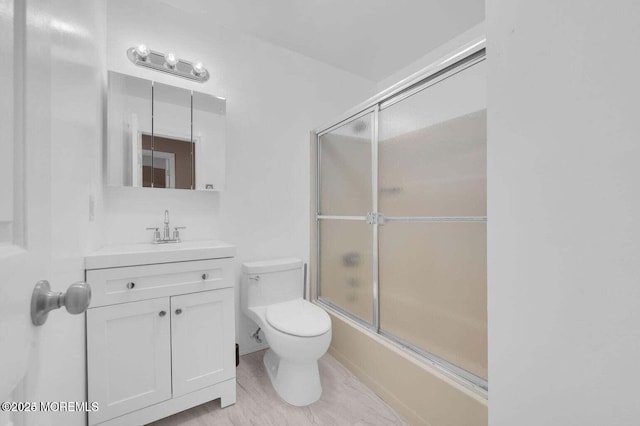 full bath with combined bath / shower with glass door, vanity, and toilet