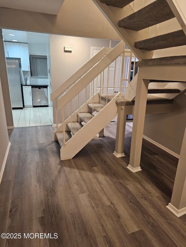 staircase featuring baseboards and wood finished floors