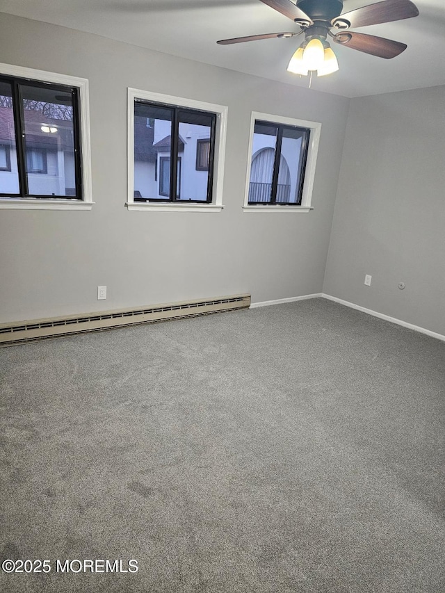 carpeted spare room featuring a baseboard heating unit, ceiling fan, and baseboards