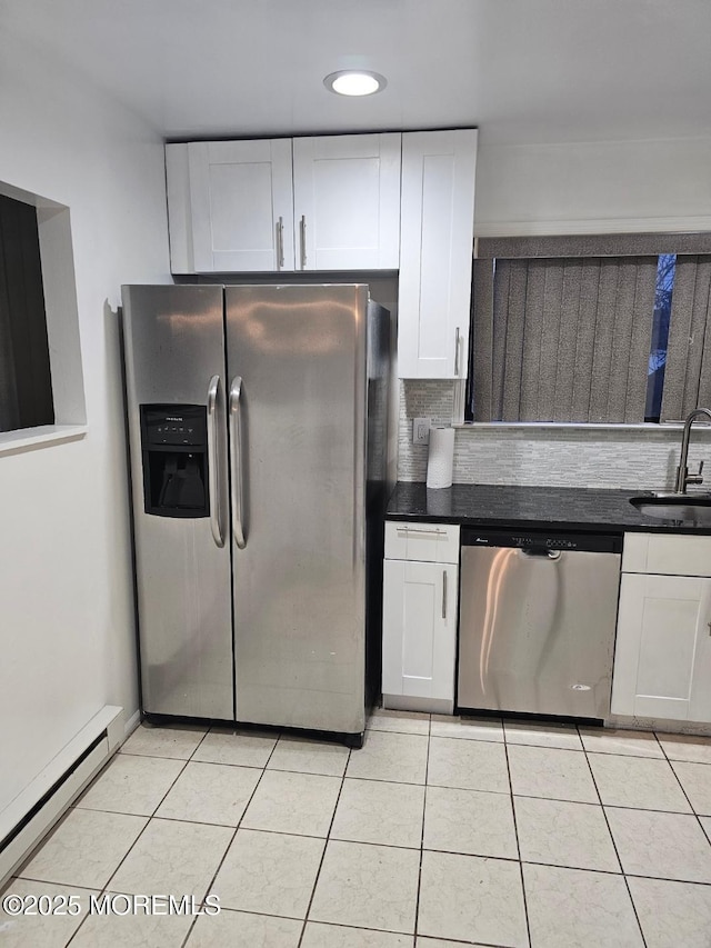 kitchen featuring stainless steel appliances, dark countertops, a baseboard heating unit, white cabinets, and a sink