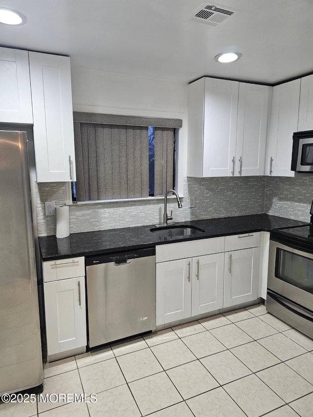 kitchen featuring light tile patterned floors, stainless steel appliances, visible vents, white cabinets, and a sink