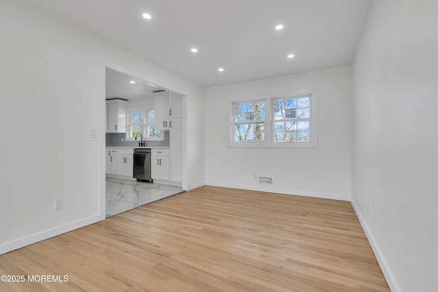 unfurnished living room with recessed lighting, light wood-style flooring, and baseboards