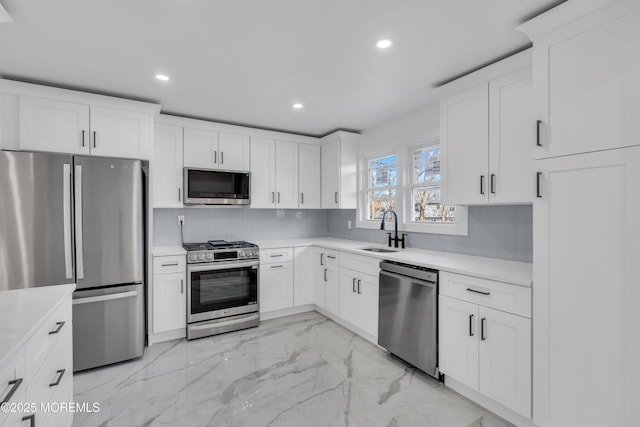 kitchen with decorative backsplash, appliances with stainless steel finishes, marble finish floor, a sink, and recessed lighting