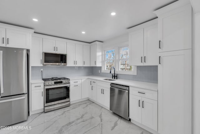 kitchen featuring appliances with stainless steel finishes, a sink, marble finish floor, light countertops, and backsplash