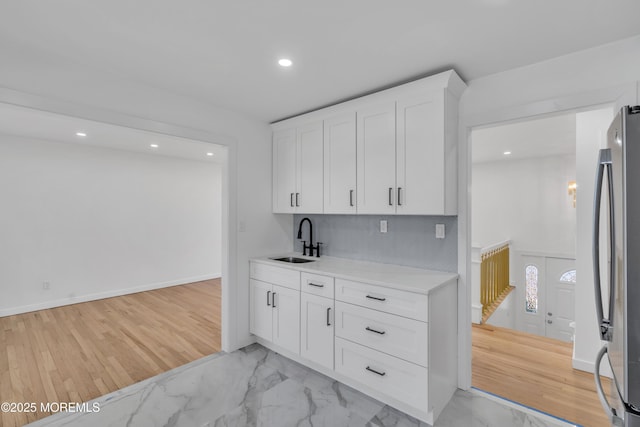 kitchen with marble finish floor, light countertops, a sink, and freestanding refrigerator