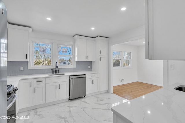 kitchen with range with gas cooktop, backsplash, stainless steel dishwasher, a sink, and light stone countertops