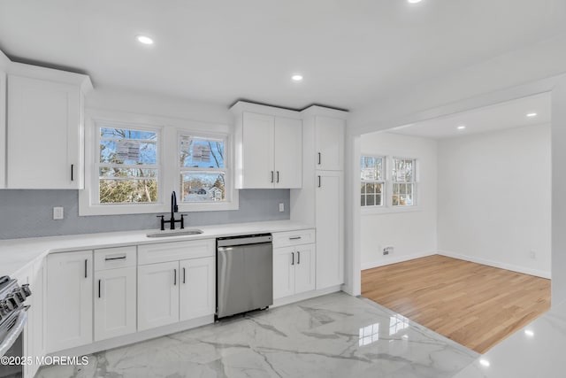 kitchen with appliances with stainless steel finishes, marble finish floor, white cabinetry, and a sink