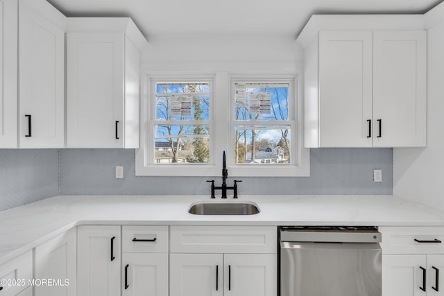 kitchen featuring dishwasher, tasteful backsplash, a sink, and white cabinetry