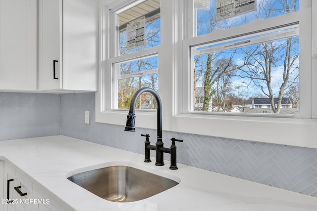 room details with white cabinetry, decorative backsplash, and a sink