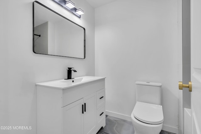 bathroom with toilet, baseboards, and vanity