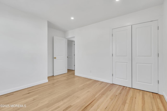 unfurnished bedroom with recessed lighting, a closet, light wood-style flooring, and baseboards