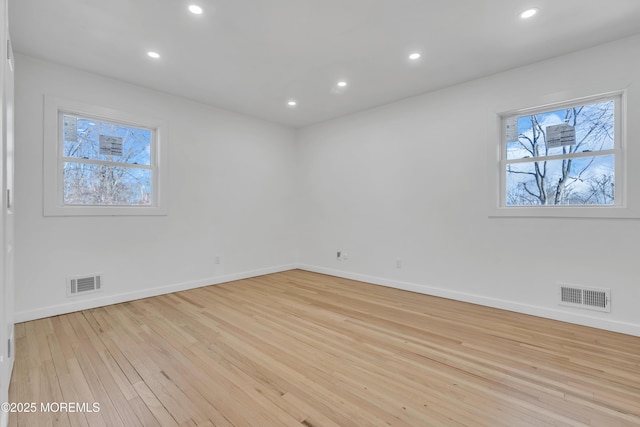 unfurnished room featuring a wealth of natural light, wood finished floors, visible vents, and recessed lighting