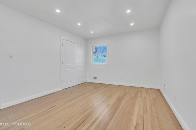 empty room featuring light wood-type flooring, visible vents, baseboards, and recessed lighting