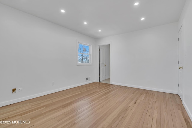 empty room featuring light wood-style flooring, visible vents, baseboards, and recessed lighting