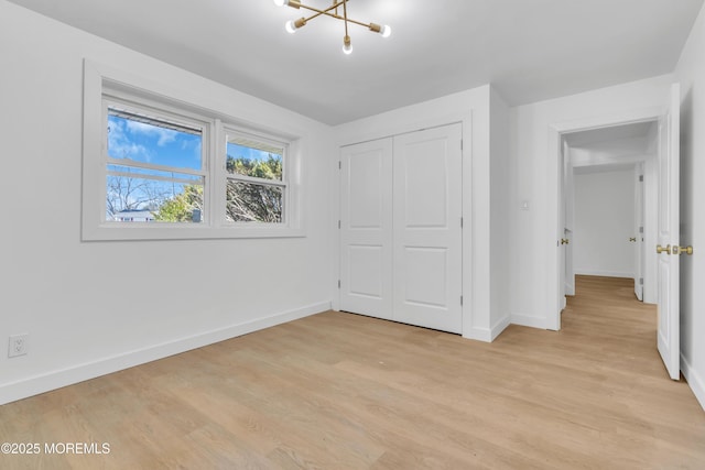 unfurnished bedroom featuring a closet, light wood-style flooring, and baseboards