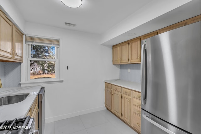 kitchen with visible vents, stove, freestanding refrigerator, a sink, and baseboards