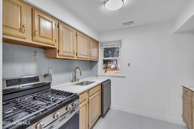 kitchen featuring tasteful backsplash, visible vents, appliances with stainless steel finishes, a sink, and baseboards