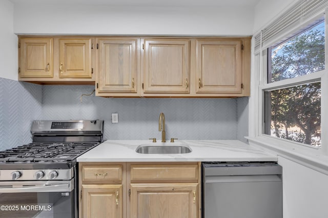 kitchen featuring light stone counters, a sink, appliances with stainless steel finishes, light brown cabinetry, and tasteful backsplash