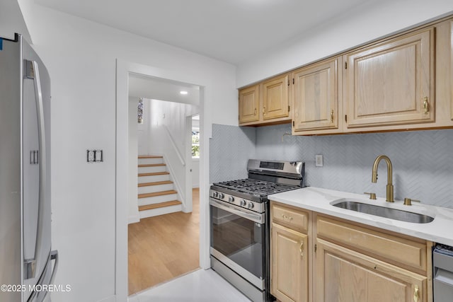 kitchen featuring stainless steel appliances, light countertops, a sink, and light brown cabinetry