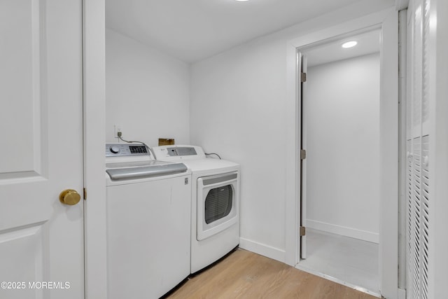 clothes washing area with laundry area, light wood-style flooring, baseboards, and washer and clothes dryer