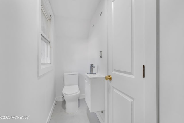 half bath with baseboards, concrete floors, vanity, and toilet