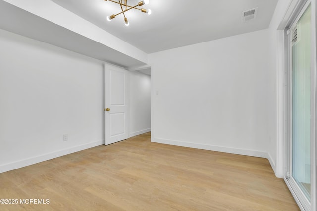 empty room with light wood-style flooring, visible vents, and baseboards