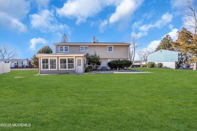 back of property with a sunroom, a chimney, and a lawn