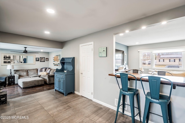 kitchen with light hardwood / wood-style floors, blue cabinetry, a breakfast bar, and ceiling fan