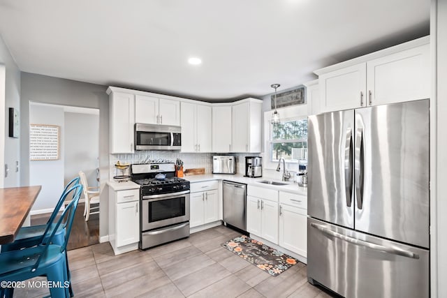 kitchen featuring sink, tasteful backsplash, decorative light fixtures, appliances with stainless steel finishes, and white cabinets