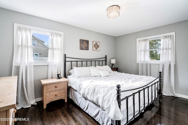 bedroom with multiple windows and dark hardwood / wood-style floors