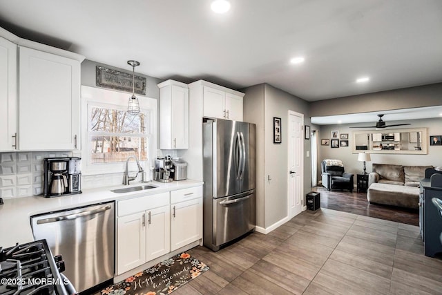 kitchen featuring appliances with stainless steel finishes, sink, hanging light fixtures, and white cabinets