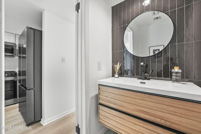 bathroom with vanity, hardwood / wood-style floors, and decorative backsplash