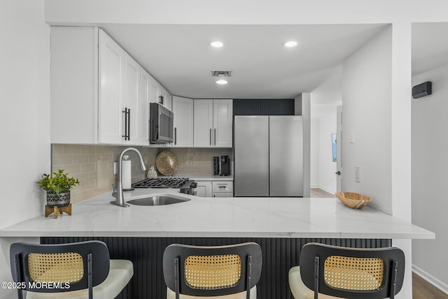 kitchen with stainless steel refrigerator, a kitchen bar, kitchen peninsula, and sink