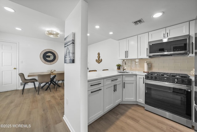 kitchen with white cabinetry, sink, stainless steel appliances, and light wood-type flooring