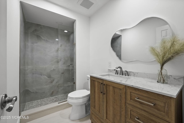 bathroom with a shower with door, vanity, and toilet