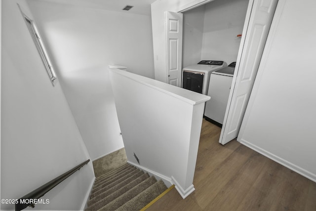 stairs with wood-type flooring and washing machine and dryer